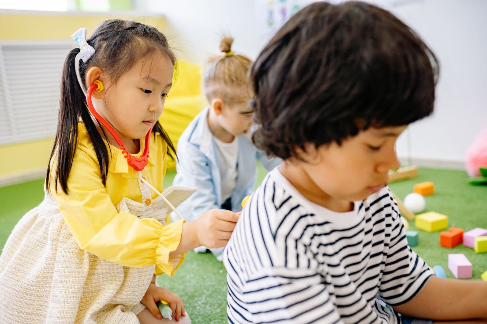 Two toddlers side by side, absorbed in handling small colourful toys.