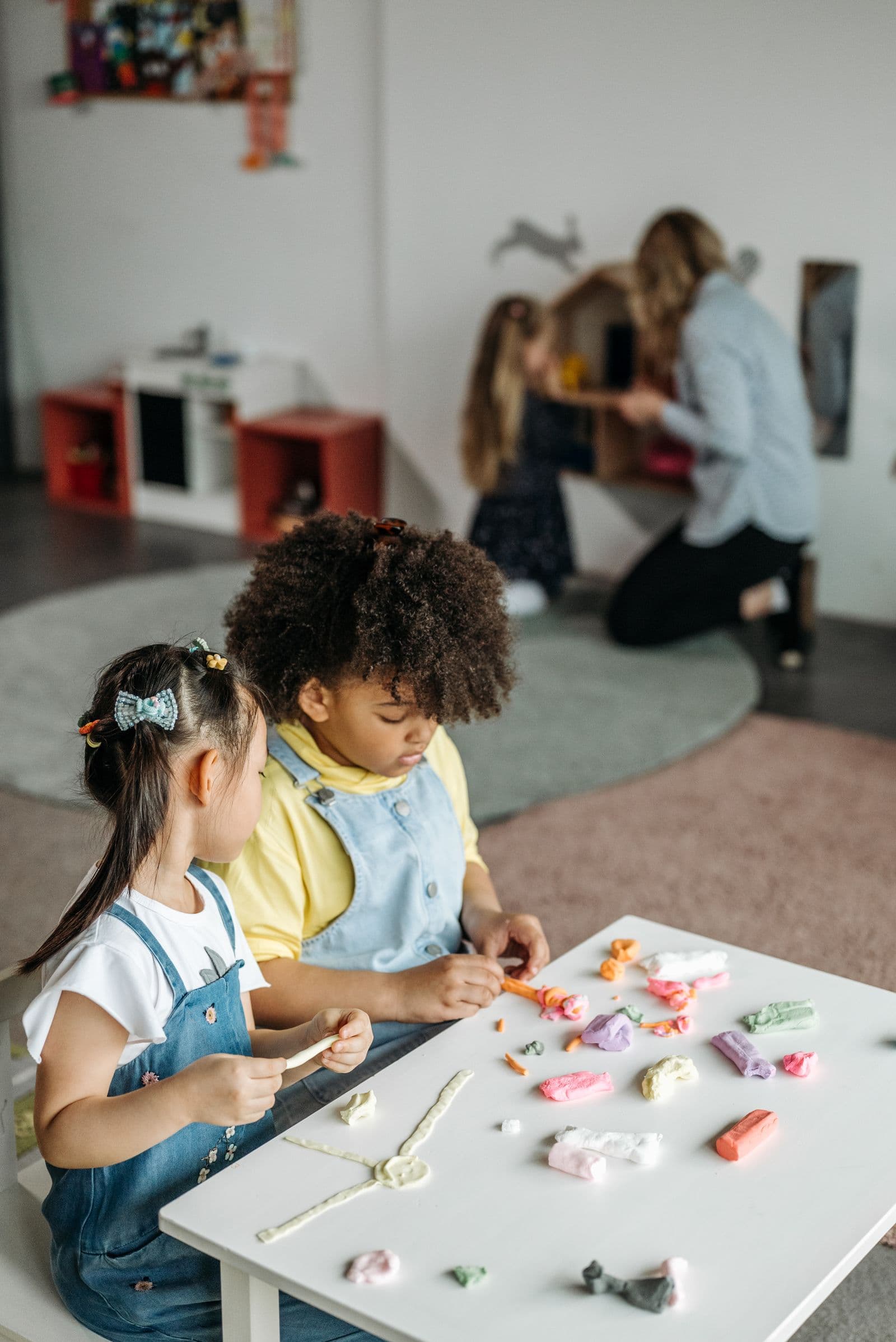 Two children in painting smocks working quietly side by side at a table.