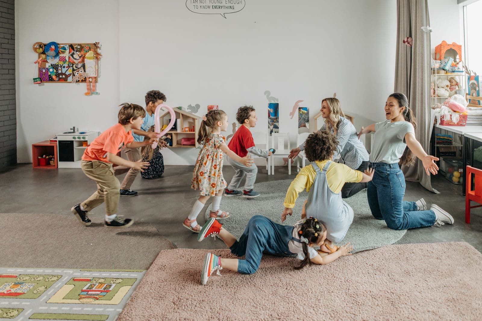 Toddlers running and playing across an open, brightly lit playroom.