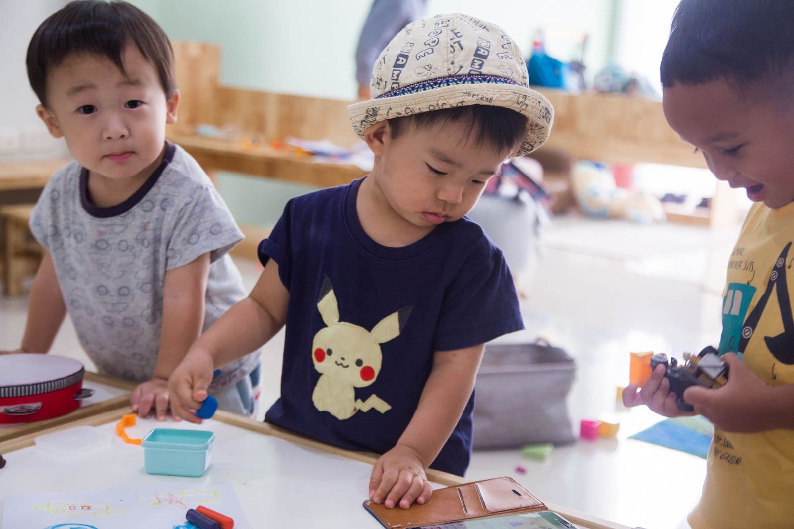 Three children drawing and writing together at a low table.