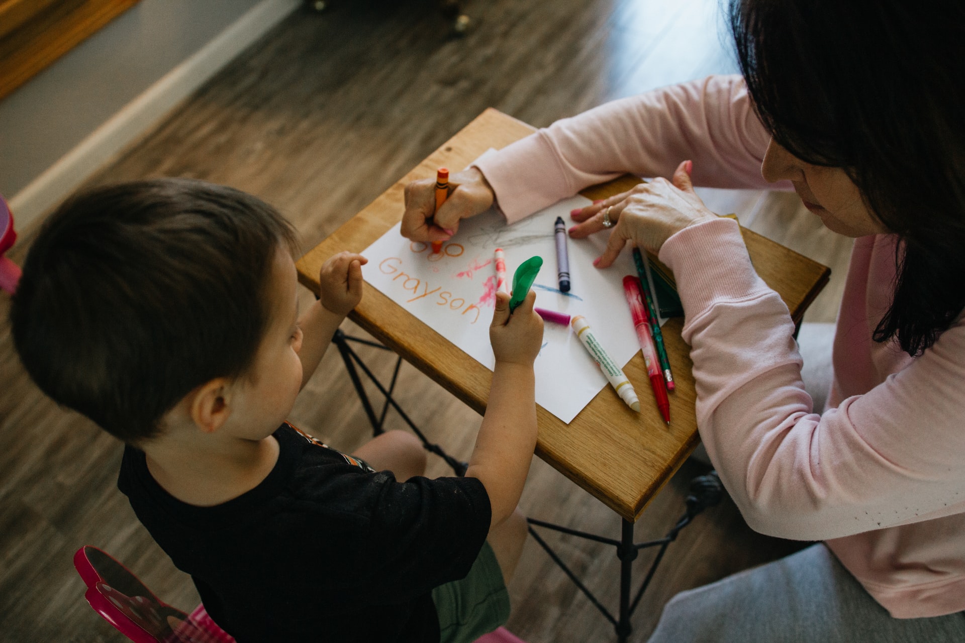 A teacher teaching a boy how to draw at birds and blossoms daycare in Sagehill